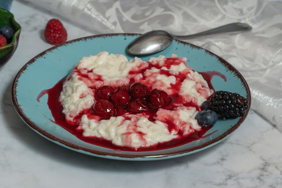 Savory rice porridge topped with sweet cherries, blackberries, and blueberries on a blue plate. Perfect breakfast or dessert.